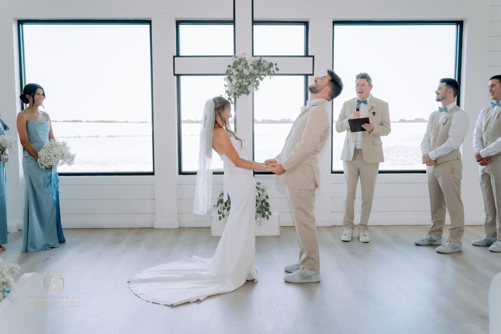 Indoor wedding ceremony in front of a large window, couple photographed with balanced light to avoid a silhouette effect