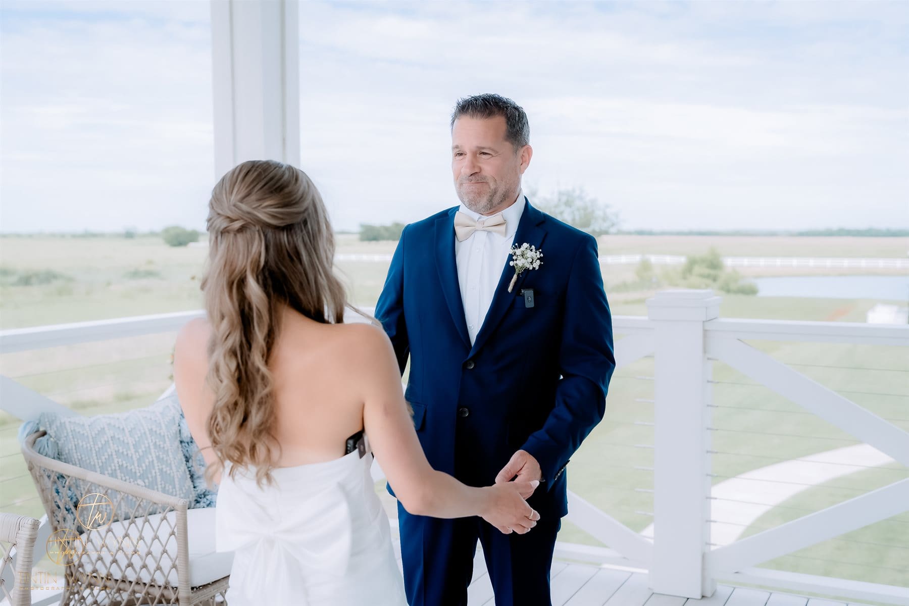 Build a Wedding Timeline Around Your Priorities Couple holding hands on a white porch, with one person in a navy suit facing the camera.