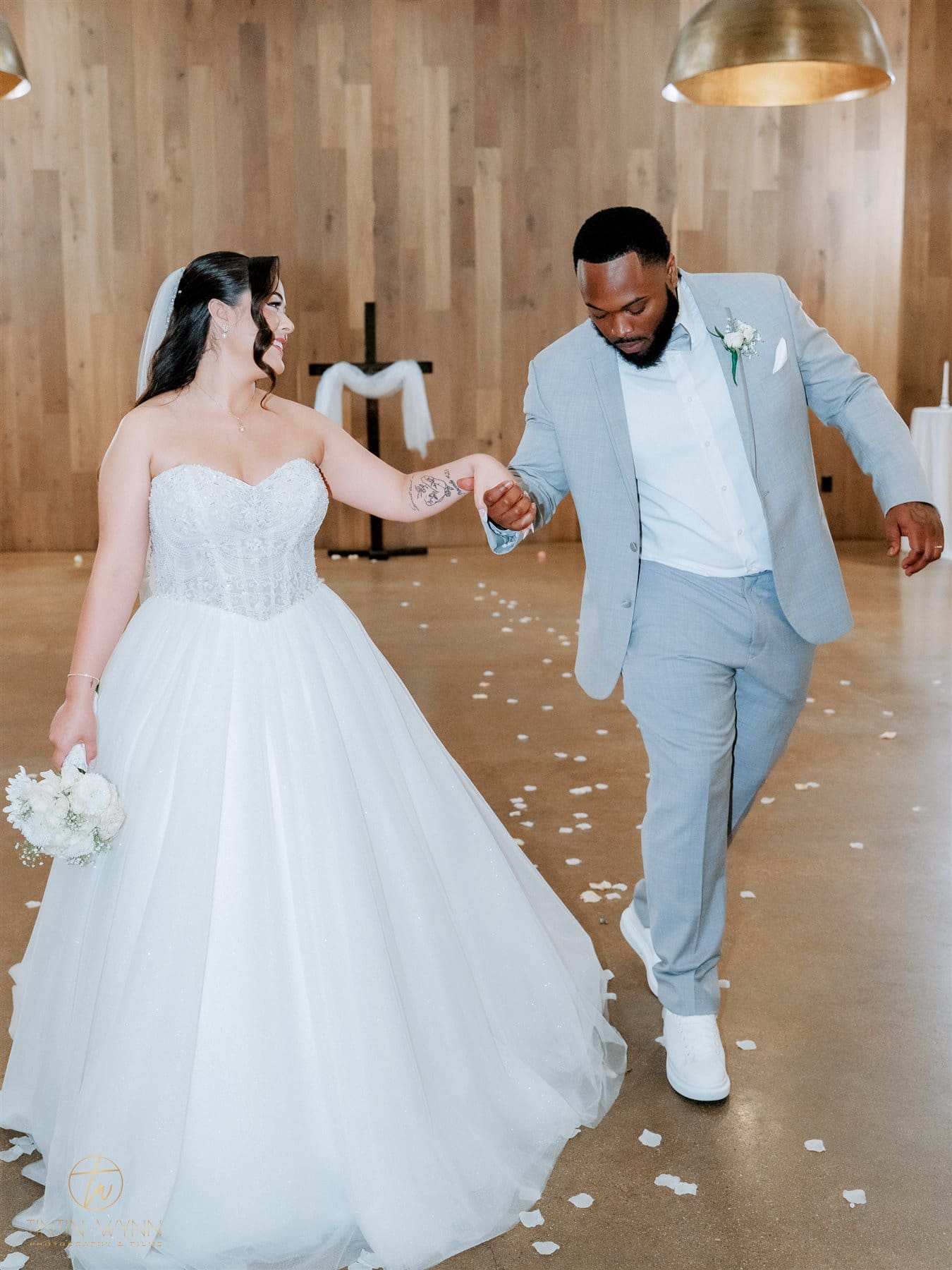 Plan Your Reception Moments and Photography Coverage Couple holding hands and dancing on a floor scattered with white petals.
